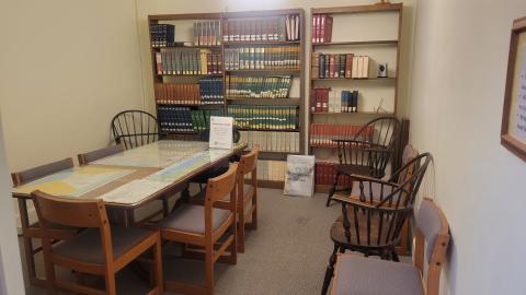 A study room with bookshelves and a table with chairs