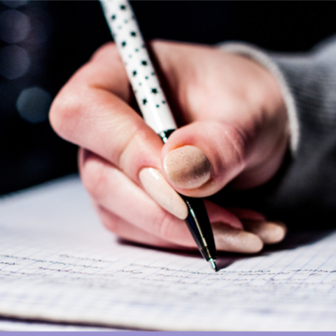 A hand holding a pen writing in a notebook